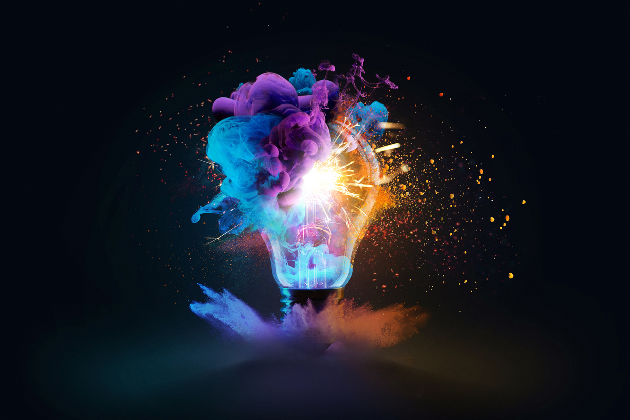 Creative light bulb explodes with colorful dry paint, sparks and splashes on a black background, concept. Think differently creative idea concept. Motion Color drop in water, Ink swirling