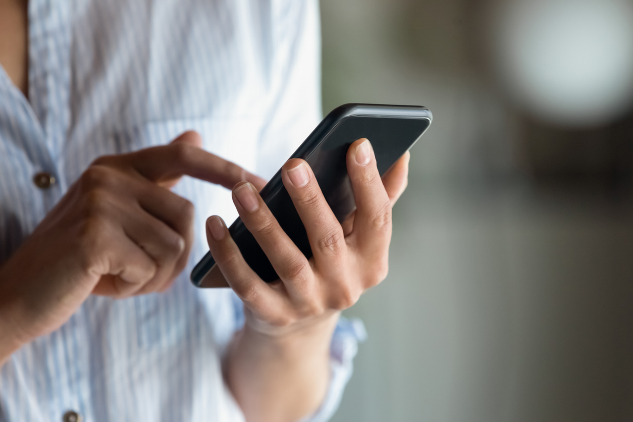 Close up woman holding smartphone in hand, typing on screen